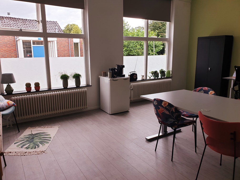De praktijkruimte van GWS Praktijk Evenwicht met een lichte spreekkamer, grote ramen en zitplaatsen aan tafel